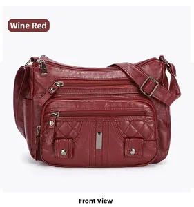 Detail view of wine red crossbody bag featuring multiple zippers and textured leather
