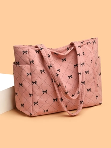 Detail of pink corduroy tote bag featuring black bow patterns and quilted diamond texture