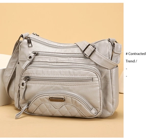 Detail of light gray washed leather crossbody bag with multiple zip pockets and quilting