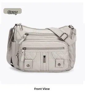 Detailed front view of gray washed leather crossbody bag with multi-zipper pockets
