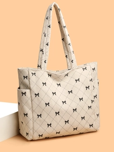 Close-up of off-white corduroy tote bag with black bow pattern and side pocket