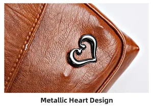 Macro view of heart-shaped metal buckle and brown pebble grain leather on crossbody bag