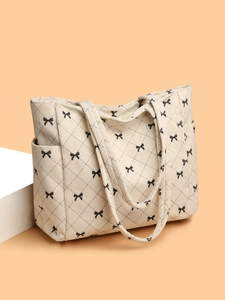 Detail of corduroy tote bag with black bow print and quilted rhombus pattern texture