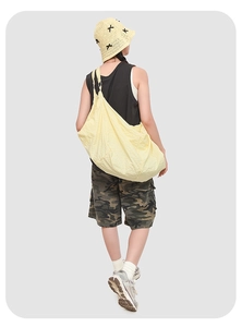 Rear view of a model wearing a large pale yellow water-resistant casual crossbody bag