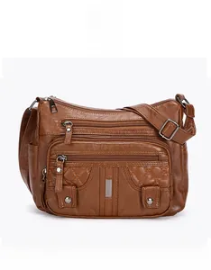 Front detail of dark brown soft leather crossbody bag featuring multiple zipper pockets