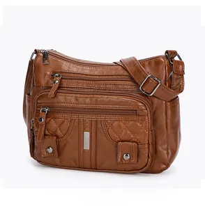 Macro side view of brown washed leather crossbody bag with quilted pockets and silver zippers