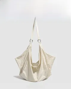 Detail view of cream water-resistant crossbody bag featuring textured geometric folds
