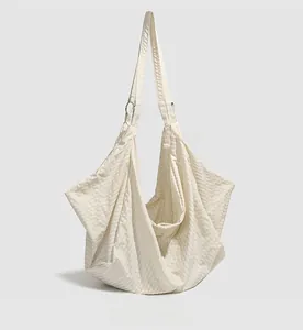 Side view of beige textured crossbody bag showing silver metal ring connectors and fabric