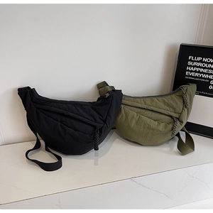 Detail of nylon half-moon crossbody bags in black and army green colors on marble