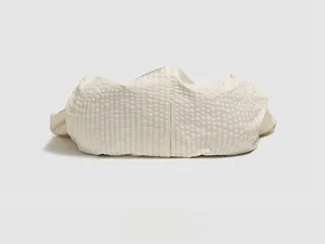 Detail view of the quilted bottom base of this white nylon crossbody bag