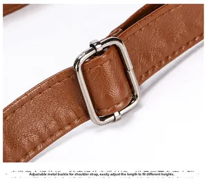 Detail of adjustable shoulder strap with silver metal buckle on brown leather bag