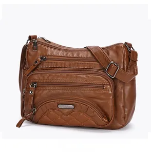 Detailed side view of brown soft leather crossbody bag featuring quilted pockets and zippers