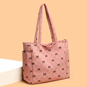 Pink corduroy tote bag with black bow print and diamond quilting shown from a 45-degree angle
