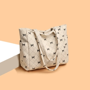 Beige corduroy tote bag with black bow patterns and quilted texture for daily use