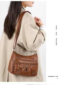 Detail of a brown leather crossbody bag with multiple zippers and vintage bronze hardware