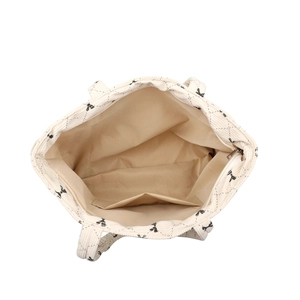 Off-white corduroy tote bag with black bow print and quilted texture in a top-down view