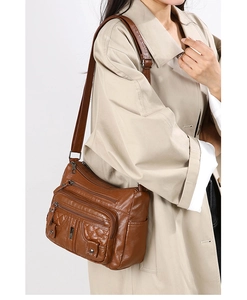 Brown faux leather crossbody bag with multiple zip pockets and quilted detail on model