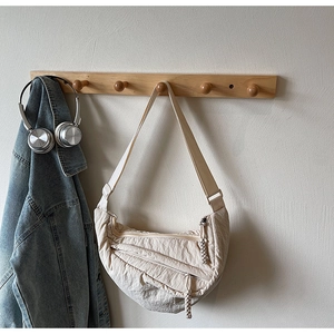 Dettaglio borsa a mezzaluna beige in nylon con tracolla larga e tessuto su gancio