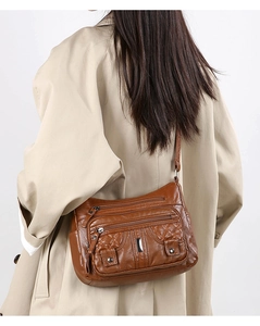 Macro view of textured brown faux leather crossbody bag with multiple zipper pockets