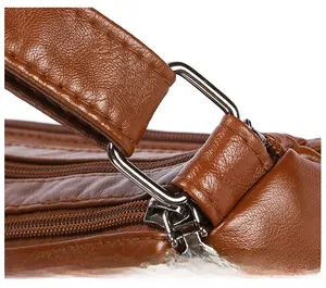 Detailed macro of silver-tone metal hardware and reinforced stitching on brown leather bag