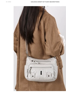 Detail of light grey multi-pocket crossbody bag with soft leather and quilted stitching