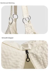Detail view of reinforced stitching and smooth zipper on beige quilted nylon tote bag