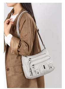 Detail of washed leather shoulder bag with quilted stitching and multi-zipper compartments
