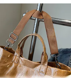 Detail of adjustable wide nylon shoulder strap on brown high-gloss tote bag finish
