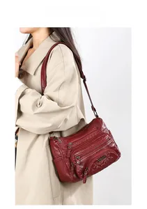 Deep red soft leather crossbody bag with multiple zippers and diamond quilted pattern