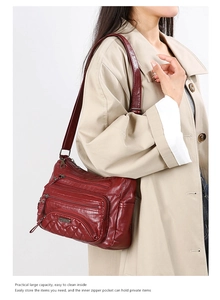Detail of red-brown faux leather shoulder bag with multiple zippered pockets on a model