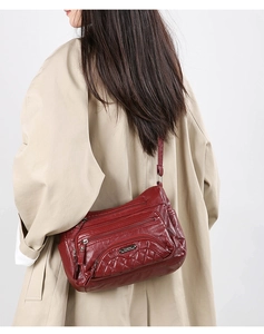 Detailed side view of burgundy soft leather crossbody bag with multiple zip pockets