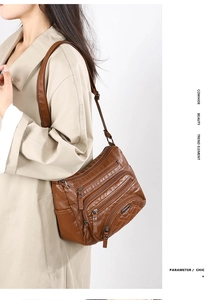 Detail of dark brown cowhide crossbody bag with multiple zippers and vintage hardware