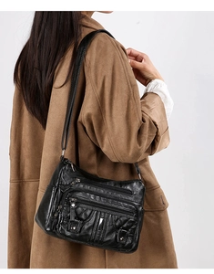 Detail view of black washed leather crossbody bag with multi-zipper pockets and quilt pattern