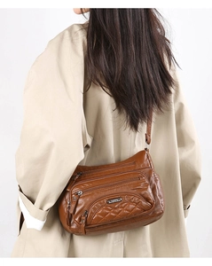Detail of dark brown leather crossbody bag with multiple zippers and quilted pattern