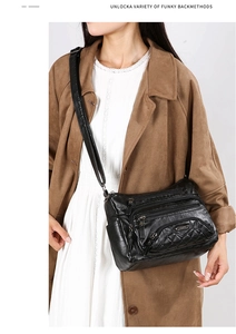 Detail of black quilted faux leather crossbody bag with adjustable strap and multiple zippers