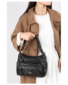 Close-up of black soft PU leather shoulder bag featuring multi-zipper pockets and quilted detail