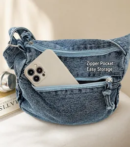 Dettaglio borsa a tracolla in denim lavato con tasche multiple a cerniera e capiente