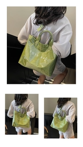 Detail of light green glossy tote bag showing TOTE BAG text and adjustable strap