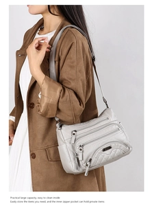 Detail of light grey soft PU leather crossbody bag with quilted pattern and zippers