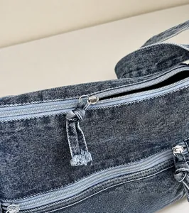 Dettaglio macro della cerniera in metallo su borsa in denim lavato con texture