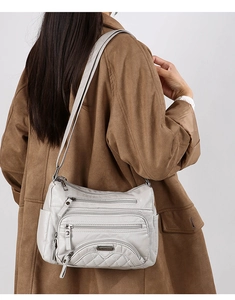 Detail of light grey multi-pocket soft leather crossbody bag with quilted patterns
