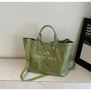 Macro detail of glossy green tote bag showing wrinkled texture and TOTE BAG print