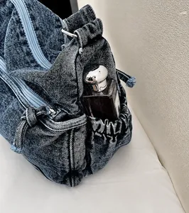 Dettaglio della tasca laterale della borsa a tracolla in denim lavato con coulisse