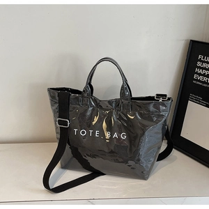 Detail of glossy tote bag with white text print and wide adjustable nylon strap