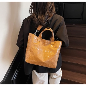 Detail of caramel brown tote bag with paper-like texture and printed lettering