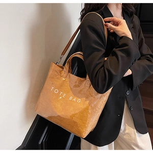 Close-up of brown textured tote bag with TOTE BAG print and silver metal hardware