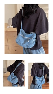 Dettagli di una borsa a tracolla in denim blu con cerniere e tracolla regolabile in tessuto