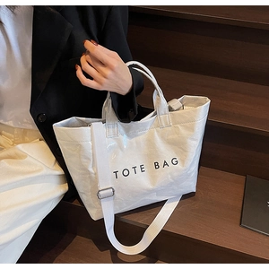 Detail of white textured tote bag with black text print on wooden stairs background
