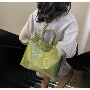 Detail of green glossy tote bag showing textile shoulder strap and TOTE BAG lettering