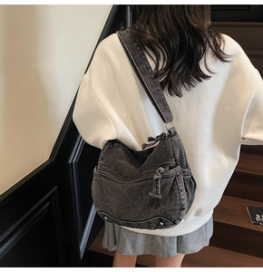 Close-up of black washed denim crossbody bag with multiple pockets and silver hardware studs